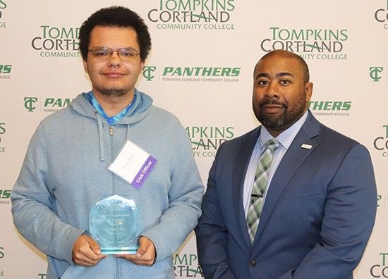 student holding award standing next to administrator