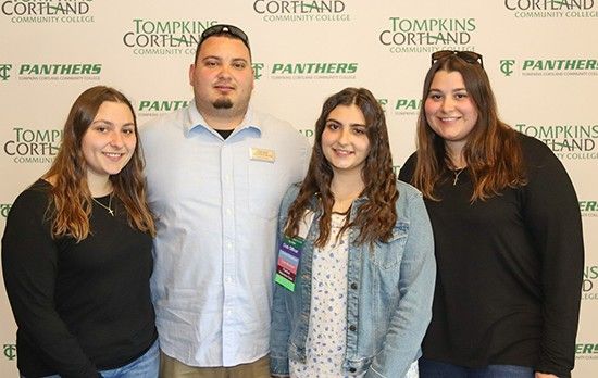 four Vigliotti siblings standing in front of backdrop