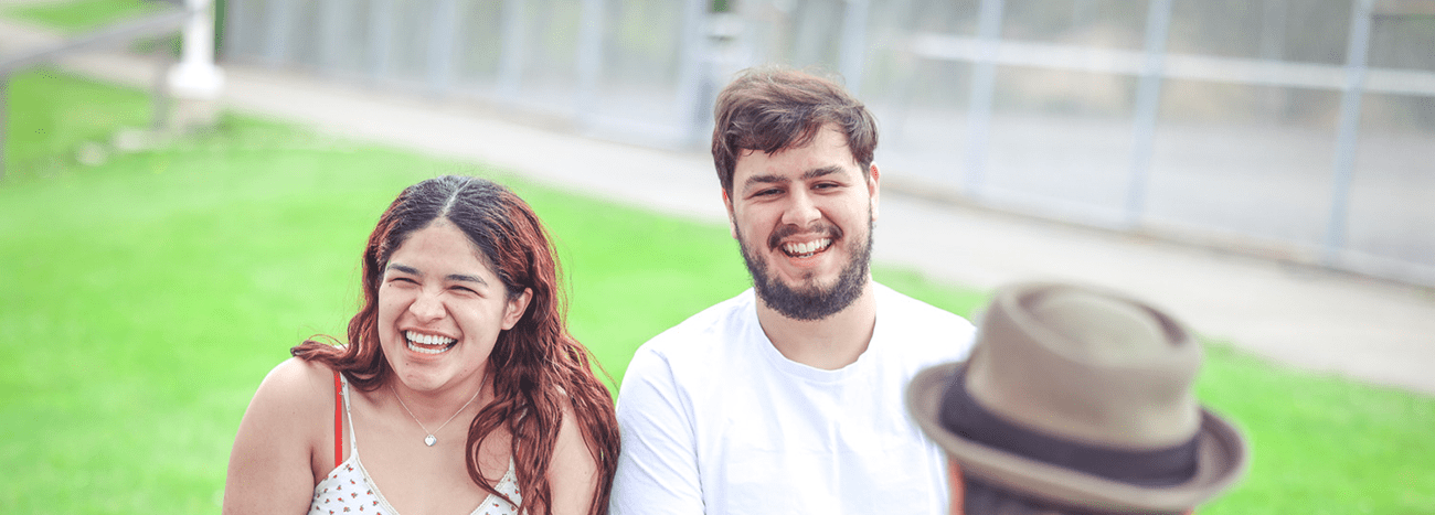 Two people sitting and laughing outdoors.